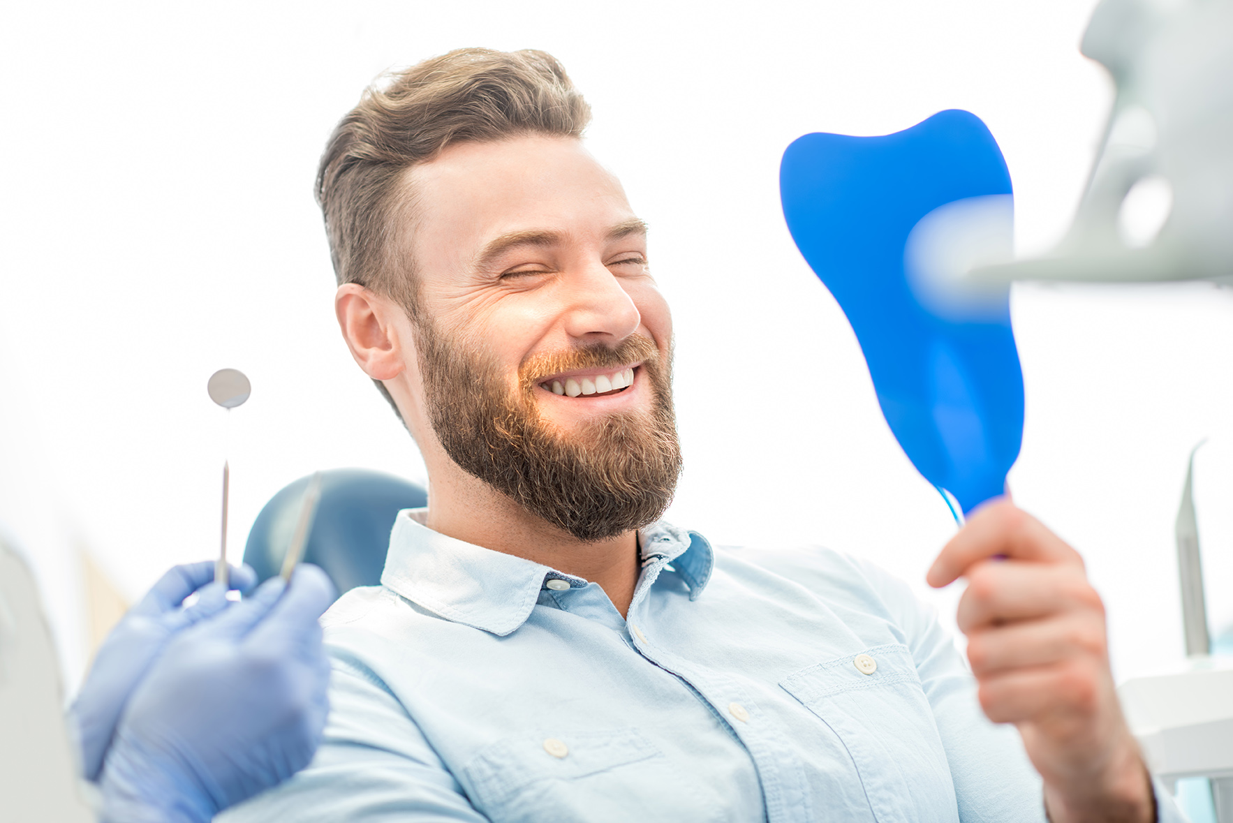 man holding up a mirror after cosmetic dentistry appointment At Timber Ridge Dental Center