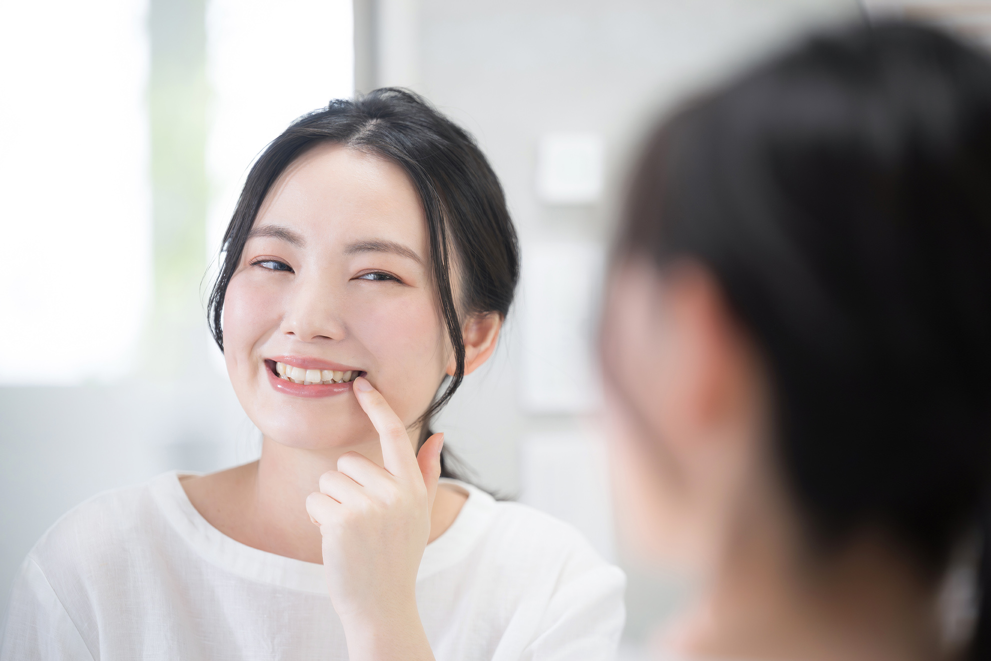 woman looking in a mirror while pointing to her painful tooth